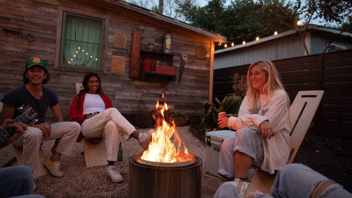 Group of friends gathered around a backyard fire pit at night